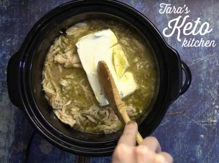 adding the cream cheese to the chili in the crockpot